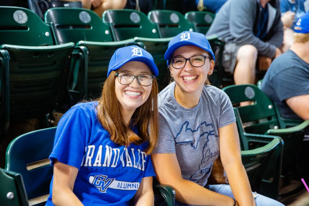 Two young GVSU students smiling in the stands of Comerica Park